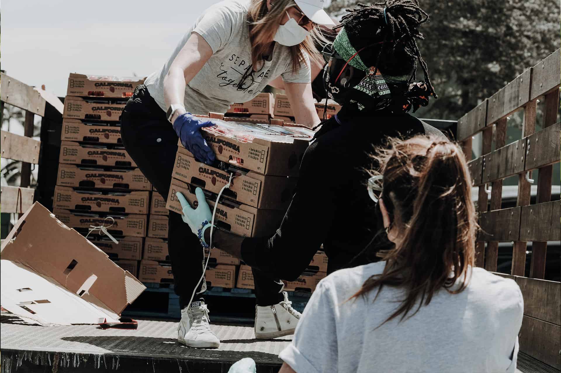 group of people unloading boxes of food from a truck